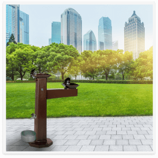 cast iron pedestal fountain in a park outside of a city